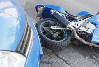 A motorcycle and car are parked on the side of the road.