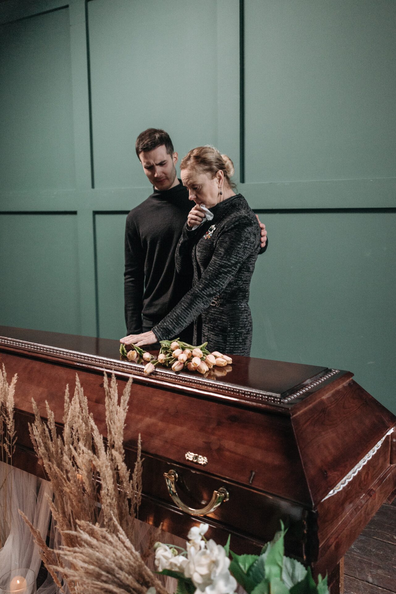 A man and woman standing next to a casket.